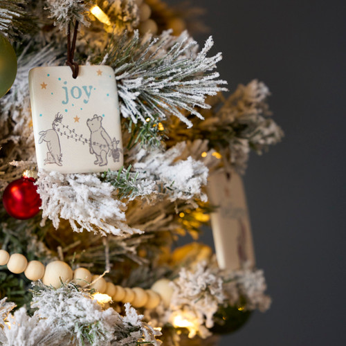 A decorated and frosted Christmas tree with different Winnie-the-Pooh ornaments displayed.