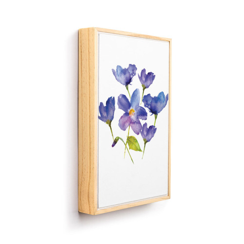 A light wood framed wall art of watercolor violets, displayed angled to the right.