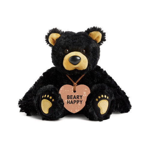 A black plush bear with brown ears, nose and paws. The bear is wearing a heart shaped painted peach colored wood ornament around its neck that says "Beary Happy".