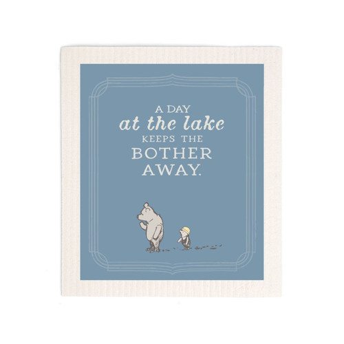 A blue biodegradable dish cloth that says "A Day at the lake Keeps The Bother Away" with an image of Pooh and Piglet at the bottom.