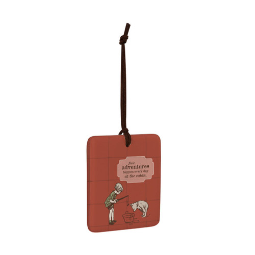 A square red hanging tile magnet ornament that says "New adventures happen every day at the cabin" with an image of Christopher Robin and Pooh fishing in a tub, displayed angled to the right.