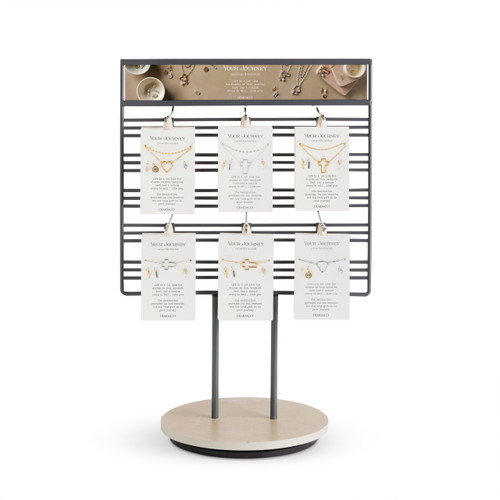 A wire table top displayer with an assortment of Your Journey jewelry and charm sets displayed on packaging cards.