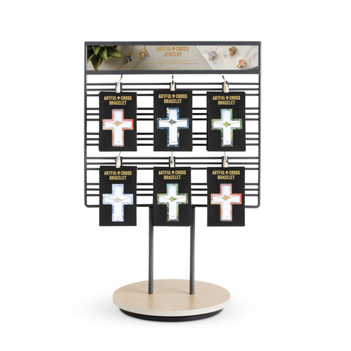 A wire table top displayer with an assortment of different Artful cross bracelets displayed in packaging.