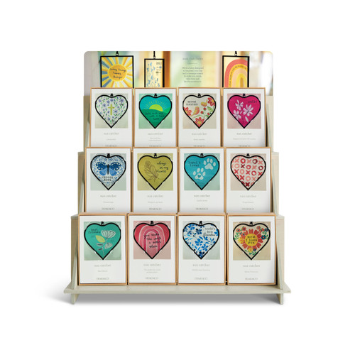 A three tier light wood counter displayer with an assortment of heart shaped suncatchers displayed in packaging boxes.