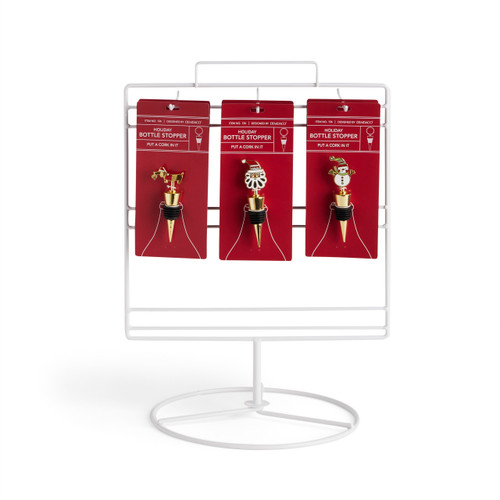 A white wire table top displayer with an assortment of holiday themed bottle stoppers.