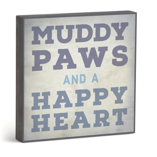 A square gray wall art with the saying "Muddy paws and a happy heart", displayed angled to the right.