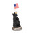 A small figurine of a black bear holding an American flag. The base of the figurine says "God Bless America", displayed angled to the right.