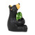 Right profile view of a sitting black bear figurine holding a large yellow sunflower with a green stem and leaves.