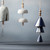 A close up image of an assortment of five hanging ceramic bells, each with metallic beads, hanging in front of a dark blue wall.