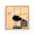 A square wood board for tic tac toe with an image of a sea gull, shown in a packaging box with a product information tag.