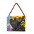 A rectangular wood hanging frame with a 2x2 inch heart shaped photo opening and has a painted image of a black bear holding sunflowers, displayed angled to the left.