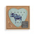 A light green heart shaped wood peg game with a moose inside a cardboard packaging box with a product tag.