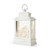 A whitewashed lit lantern with a white nativity scene inside, displayed angled to the left.
