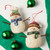 Two paper pulp snowmen ornaments in hats and scarves, displayed on a green and white background.