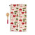 A tan kitchen towel with red and green tools for holiday baking next to a wood spoon with a red handle, shown with the towel laid out in its full size.