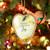 A hanging heart shaped wood ornament with a yellow and cream artwork inside inspired by ArtLifting artist Grace Goad. The ornament says "Wishes for a season full of Joy", displayed hanging in a lit Christmas tree.