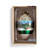 An onion shaped hanging ornament with an image of a winter Swiss Chalet around the middle and silver glitter around the top and bottom inspired by artwork from ArtLifting artist Lucas Farlow, displayed in a packaging box.