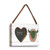 A rectangular hanging white wood frame ornament with a graphic image of a green horned animal skull and a 2x2 heart shaped opening for a photo, displayed angled to the right.