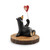 A black bear sitting on a wood stump and holding a heart shaped balloon of the Canadian flag.