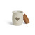 A cream ceramic candle with a gray heart. The candle has a cork lid, displayed with the lid off and leaning against the side of the candle.