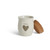 A cream ceramic candle with a gray heart and the word "xoxo". The candle has a cork lid, displayed with the lid off and leaning against the side of the candle.