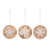 A set of three whitewashed wood ornaments each with a different snowflake image on the front.