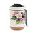 A white travel mug with a cork base, a black lid, and a watercolor image of an apple blossom, displayed with a product tag attached.