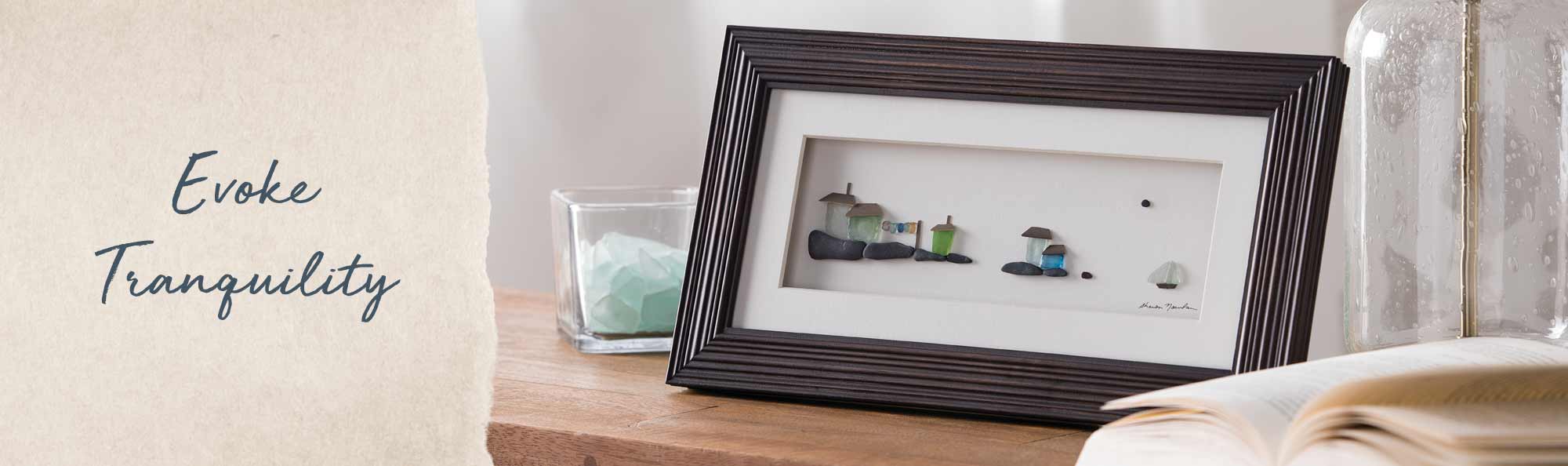 Evoke Tranquility. Framed pebble art sitting on a table. 