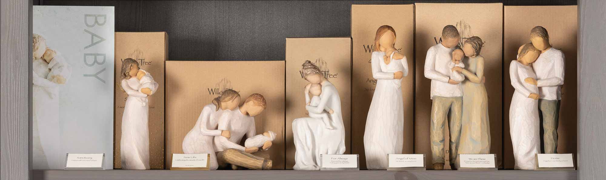 Willow Tree hand carved figures displayed on a store shelf with a sign that says BABY