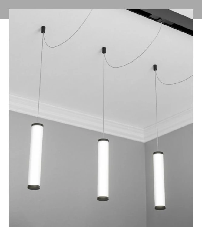 Three modern, white cylindrical pendant lights with black caps hang at staggered heights from a black track on a white ceiling.