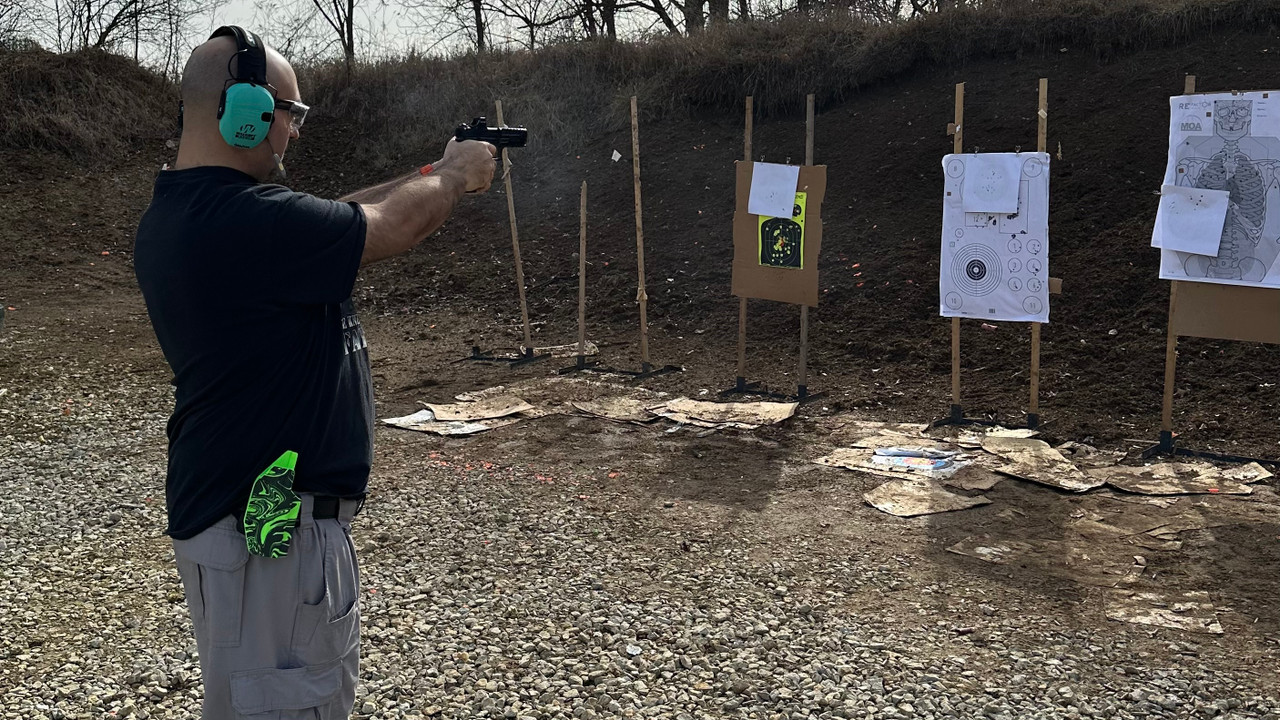 man firing a pistol at a paper target