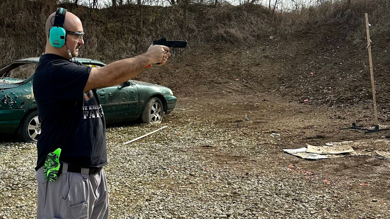 man standing with pistol in hands, aiming at target