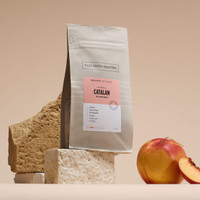 300g bag of Catalan 'Red Bourbon' on beige stone brick, next to a fresh nectarine and slice.