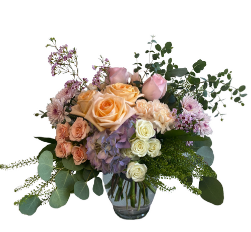 Peach and blush rose arrangement with lavender hydrangea and seasonal garden blooms.