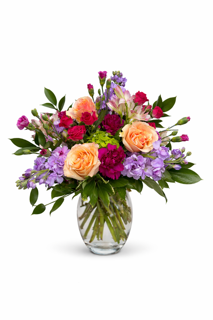 Peach and lavender floral arrangement with pink blooms in a loose garden-style design.