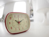 The glow-in-the-dark clock face features large, easy-to-read numbers that are printed in a crisp, clear font. The clock hands are also easy to see, with a contrasting red second hand that makes it easy to track time. || Glow-in-the-Dark Red Retro Alarm Clock, 4" AC/K/LI/08-R || Lindenhaus Imports in Helen, Ga