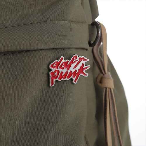 The iconic rock band Daft Punk pin fastened to a green backpack. The iconic rock band Daft Punk pin fastened to a green backpack.