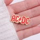 AC/DC Hard Enamel Pin held in palm of hand.