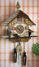 View of Inga Musical Chalet with Steeple German Quartz Cuckoo Clock hanging on decorative pink and white stripped wall