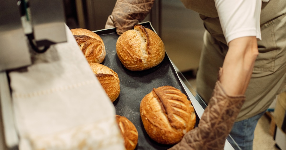 A bubbly sourdough starter has airy holes and a thick texture as it rests in a container during fermentation