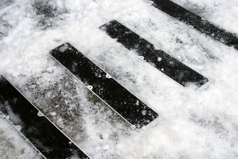 Heskins Bolt Down Anti-Slip Plates providing traction on outdoor steps in snowy winter conditions — heavy-duty pre-drilled plates rated for freeze-thaw exposure (shown with standard grit; photoluminescent glow version available for low-light egress)