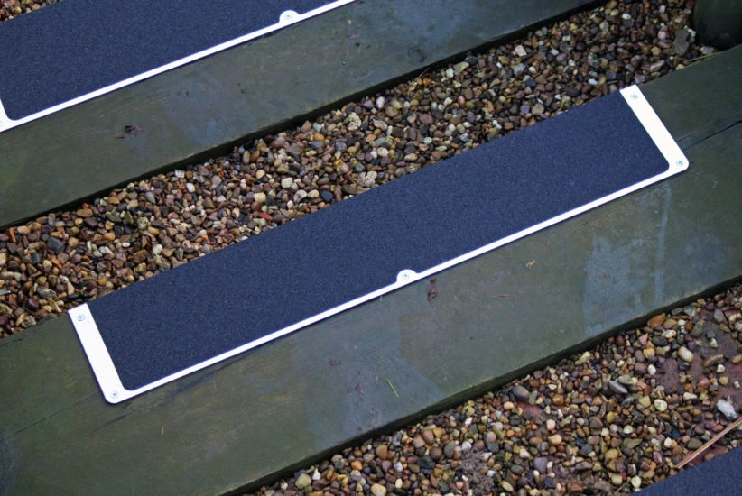 Two Heskins L-Shape Bolt Down Anti-Slip Plates installed side-by-side on outdoor wooden steps — 25" plates can be edge-joined for wider stair coverage