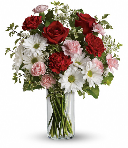 The fragrant bouquet includes white Asiatic lilies and red roses accented with fresh greenery delivered in a classic clear glass vase.
