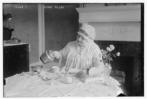 HistoricalFindings Photo: Olive Kline,Woman Seated at Table,Having Tea,Fireplace,Flowers