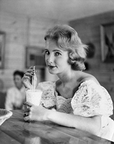 Posterazzi Portrait of a young woman drinking a milkshake at a bar counter Poster Print (18 x 24)