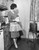 Posterazzi Side profile of a young woman looking at a television in the kitchen Poster Print (18 x 24)