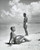 Posterazzi Side Profile Woman Sitting with Young Man Standing on Beach Poster Print (18 x 24)