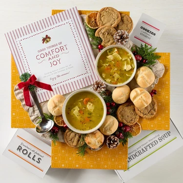 Soup package with a decorative insert, with two bowls of soup, rolls and cookies.