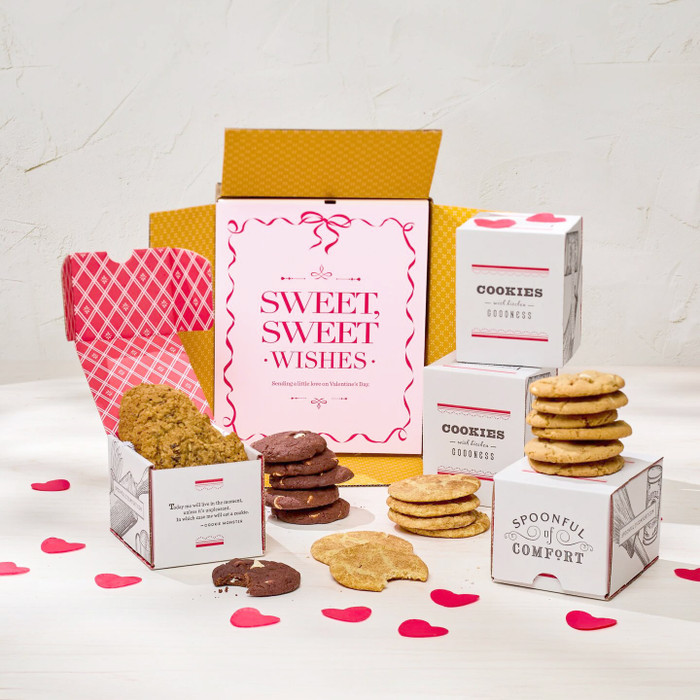 Valentine’s cookie gift arrangement with assorted cookies, heart-shaped confetti, and a pink card that reads “Sweet Sweet Wishes.”