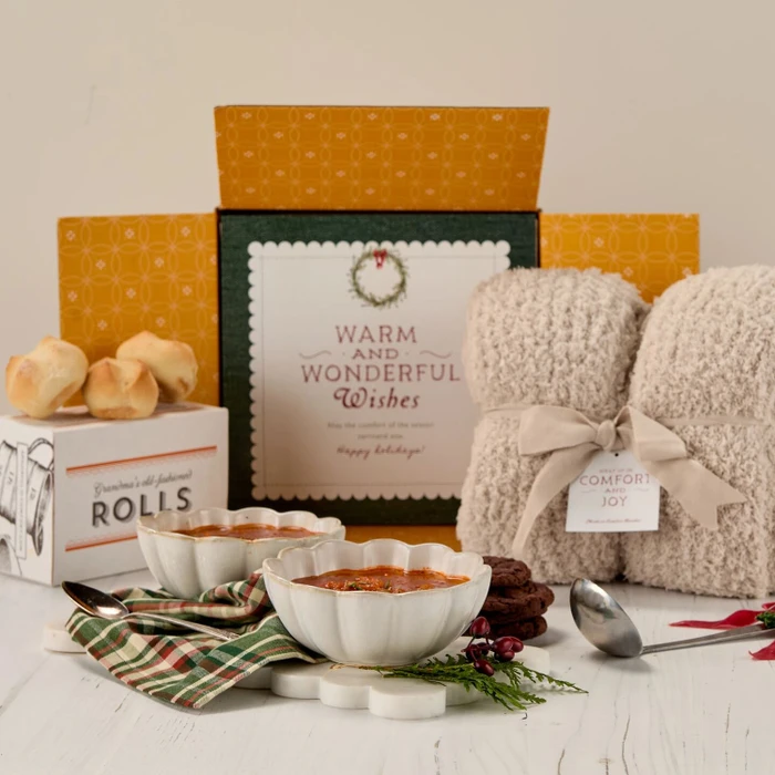Soup package with a decorative insert, with two bowls of soup, rolls and cookies, with a cozy warm blanket